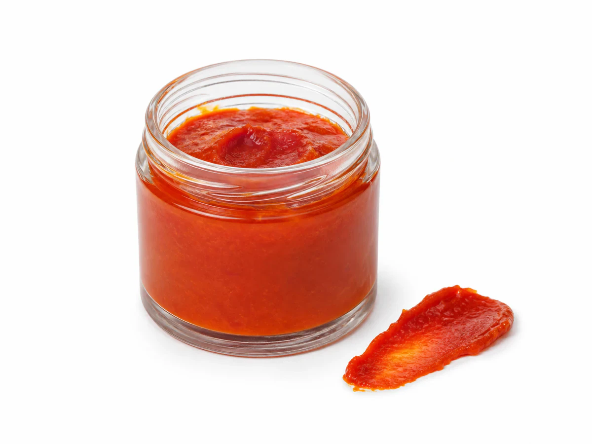 Semi-solid orange-red crude palm oil in a laboratory sample jar