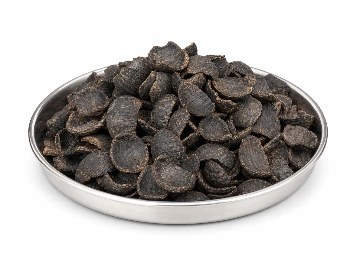 Pile of hard dark-brown palm kernel shell fragments used as biomass fuel